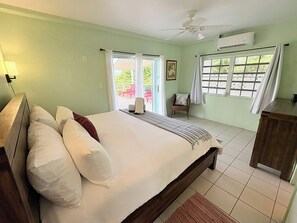 A bedroom with a bed, a nightstand, a chair, and a window with curtains.