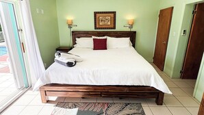 Une chambre avec un lit en bois, une couvre-lit blanche, deux lampes fixées au mur et un tableau encadré accroché au mur.