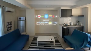 A modern living room with a sofa, a coffee table, and a TV wall displaying streaming services. - sincereresidence (Osaka)