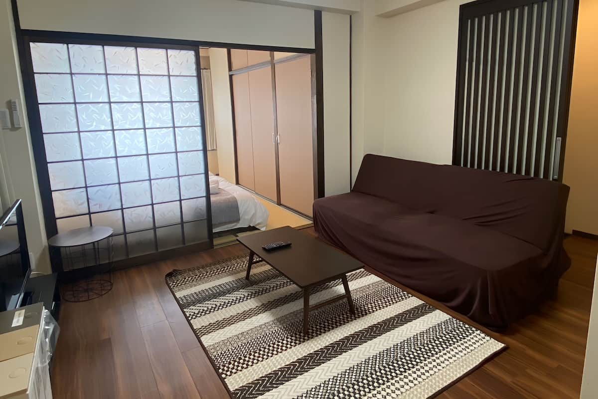 A room with a sofa, a small table, a patterned rug, and a sliding door with frosted glass panels.