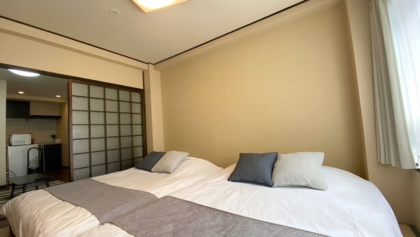A hotel room with two beds, a kitchenette, and a sliding shoji screen. - sincereresidence (Osaka)