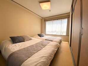 A hotel room with two beds, a wardrobe, and a window with sheer curtains. - sincereresidence (Osaka)