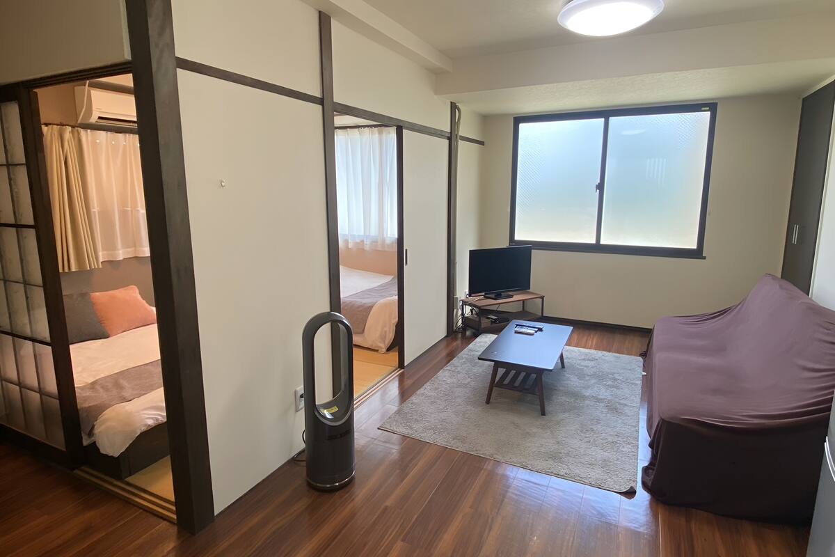 A modern room with a bed, a sofa, a TV, and a window.