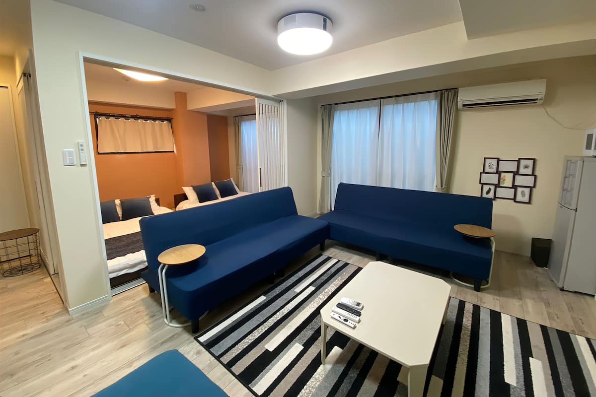 A modern living room with a blue sectional sofa, a white coffee table, and a striped rug.