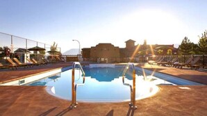 A swimming pool with sunbathing chairs and a lifeguard stand.