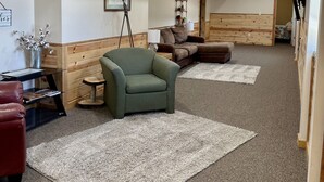 A spacious hallway with a green armchair, a wooden bench, and a small table with a lamp.