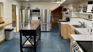 A spacious kitchen with stainless steel appliances, a wooden table, and a blue floor.