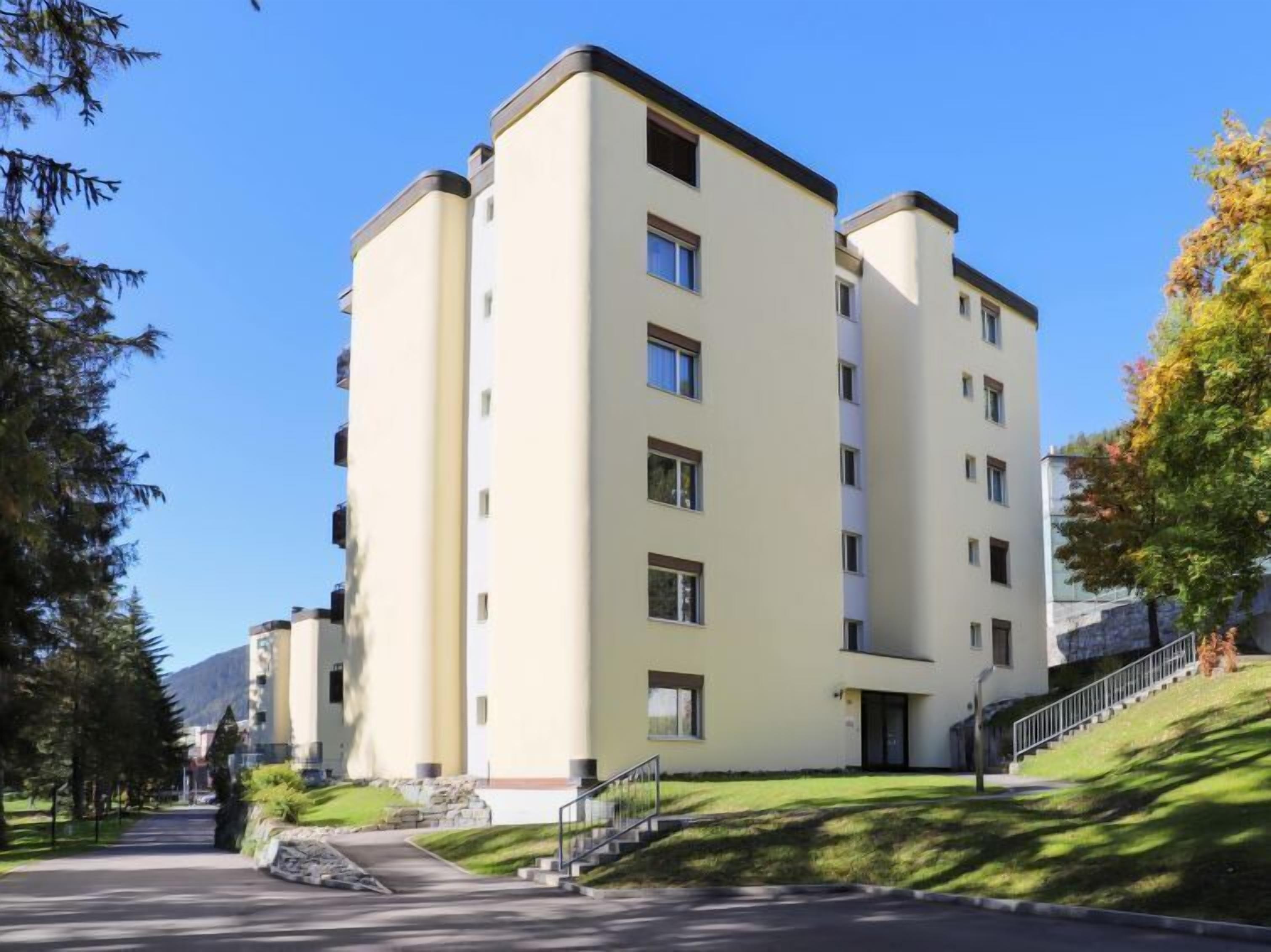 A multi-story building with a modern architectural design, featuring a flat roof and a symmetrical facade.