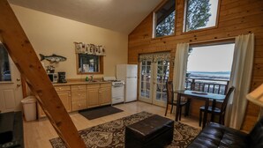 A cozy cabin interior with a kitchen, dining area, and a view of the ocean. -  'Chisik Cabin'  Waterfront/Sunset Views (Kasilof)
