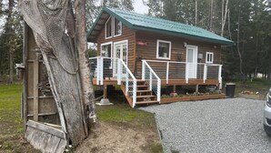 A wooden cabin with a green roof, a deck, and a staircase leading to a porch. -  'Chisik Cabin'  Waterfront/Sunset Views (Kasilof)