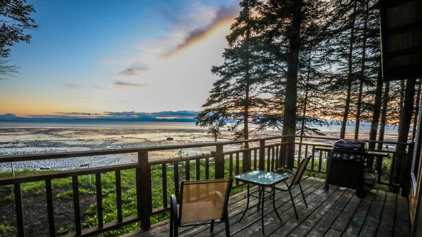 A wooden deck with a view of a beach and mountains, a grill, and outdoor seating. -  'Chisik Cabin'  Waterfront/Sunset Views (Kasilof)