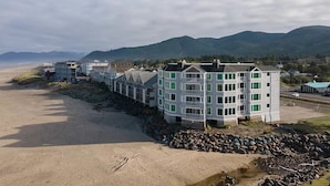 Un hotel sulla costa con diversi piani, vista sulla spiaggia e un litorale roccioso.