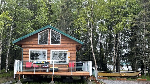 Une cabane en bois dotée d’un balcon, entourée d’arbres.