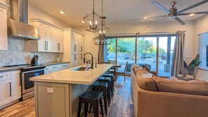 A modern kitchen with a large island, white cabinetry, and a ceiling fan. - ADOBE MANOR // Main + Guest Home // Sleeps 20 (Mesa)