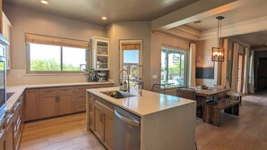 A modern kitchen with a central island, wooden cabinets, and a view to the outdoors. - ADOBE MANOR // Main + Guest Home // Sleeps 20 (Mesa)