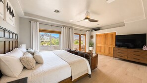 Une chambre à coucher avec un lit, une télévision, une armoire en bois et une fenêtre avec des rideaux.