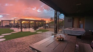 A patio area with a wooden table, a covered seating area, and a view of the sunset. - A D O B E  -  E S T A T E (Mesa)