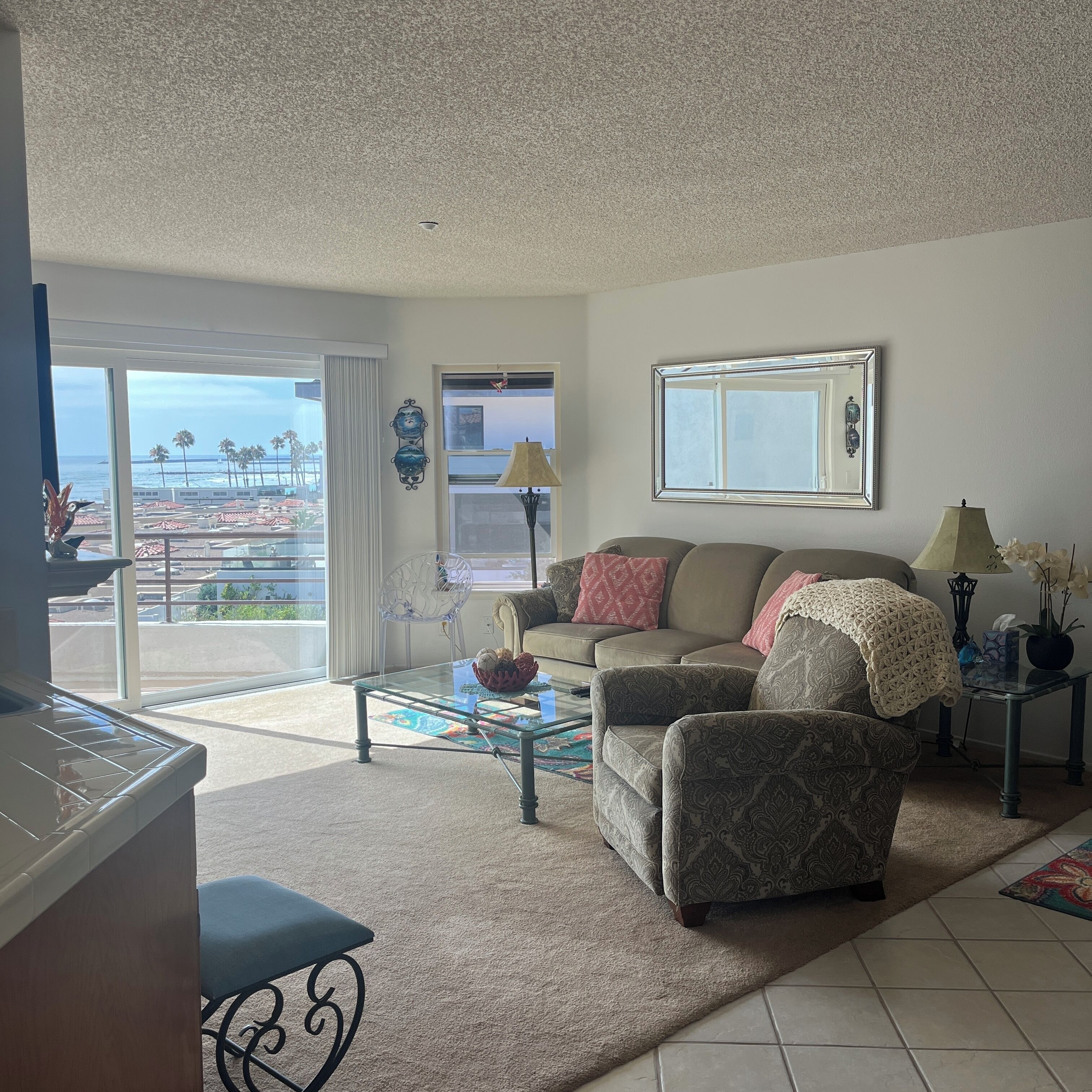 Uma sala de estar com sofá, poltronas, mesa de centro e vista para a praia.