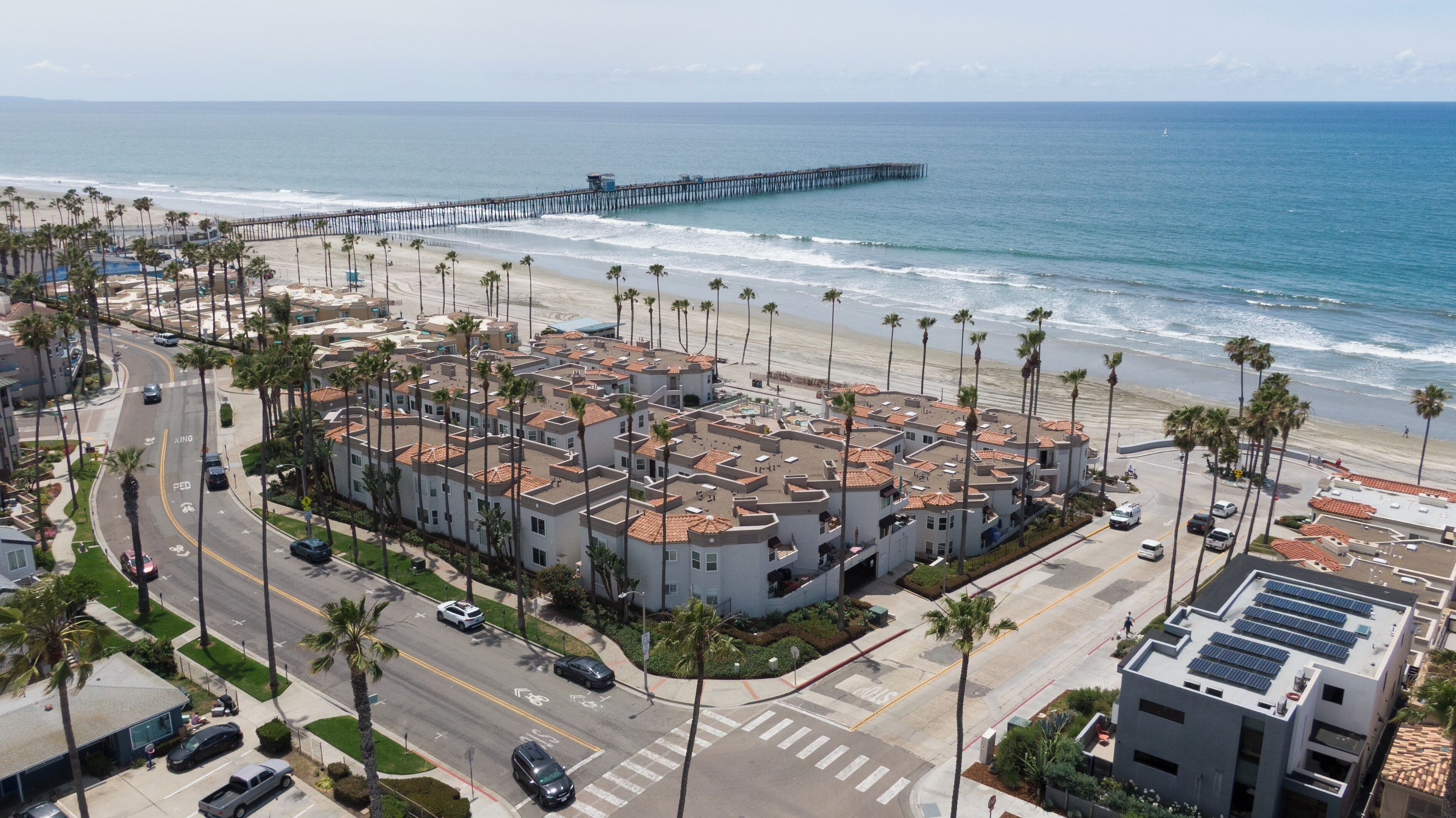 Una zona residencial costera con playa, un muelle y una hilera de edificios de apartamentos.