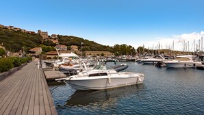 Ein Yachthafen mit vertäuten Booten, einer Holzpromenade und Gebäuden im Hintergrund.