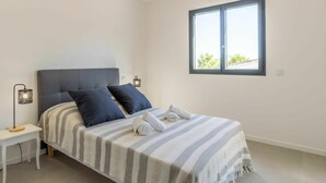 Ein Schlafzimmer mit einem Bett, zwei Nachttischen, einem Fenster und einem Beistelltisch.