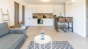 Eine moderne Wohnung mit Wohnbereich, Küchenzeile und Essplatz.