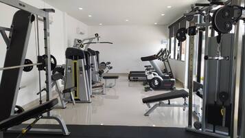 Een fitnessruimte met diverse trainingsapparaten, waaronder loopbanden en gewichten.