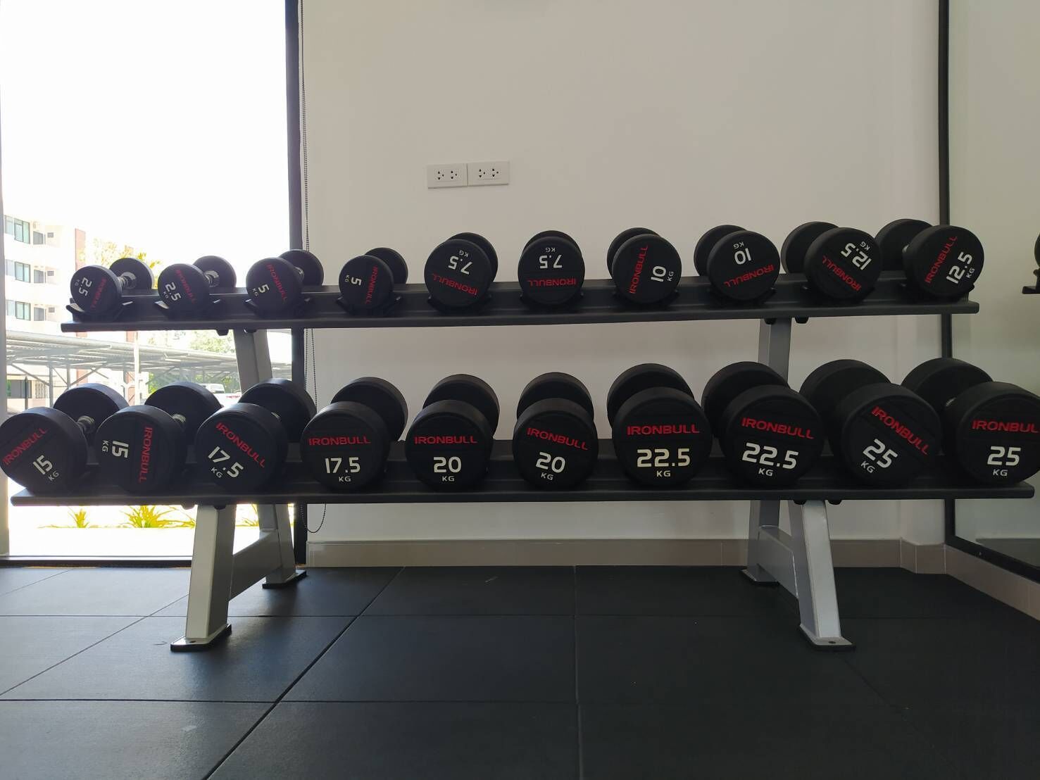 A rack of IronBull weightlifting dumbbells in a gym.
