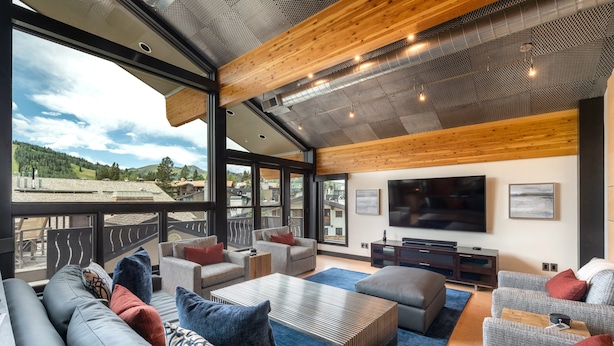 A spacious living area with a large TV, comfortable seating, and a view of the outdoors. - Unrivaled Luxury Penthouse Ski In Ski Out 3 Bed+Den Modern Views Silver Lake Village Deer Valley (Park City)