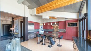 A modern kitchen with a central island, stainless steel appliances, and red cabinetry. - Unrivaled Luxury Penthouse Ski In Ski Out 3 Bed+Den Modern Views Silver Lake Village Deer Valley (Park City)