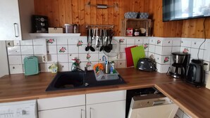 A kitchen with wooden cabinets, a sink, a toaster, and a coffee maker. - Fitter and guest house in Groß Rossau - entire house (Osterburg (Altmark))