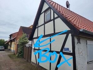 Une maison traditionnelle à colombages, avec un toit rouge à pignons et des tuiles, une antenne parabolique et une porte de garage.