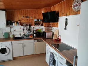 Une cuisine avec des murs en bois, un lave-linge, une machine à café et une horloge.