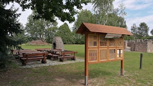 A picnic area with benches and a stone oven, surrounded by a stone wall and trees. - Fitter and guest house in Groß Rossau - entire house (Osterburg (Altmark))
