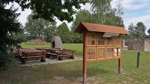 Un espace pique-nique équipé de bancs et d’un four en pierre, entouré d’un mur de pierre et d’arbres.