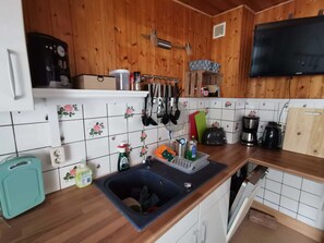 Eine Küche mit Holzausstattung, einer Kaffeemaschine, einem Toaster, einem Spülbecken und einem an der Wand befestigten Fernseher.