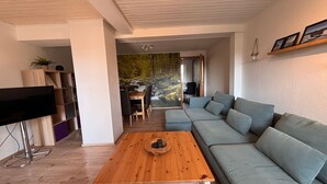 A modern living room with a sectional sofa, a wooden coffee table, and a TV. - Apartment Hohensee ground floor - Ferienwohnung Hohensee (Clausthal-Zellerfeld)