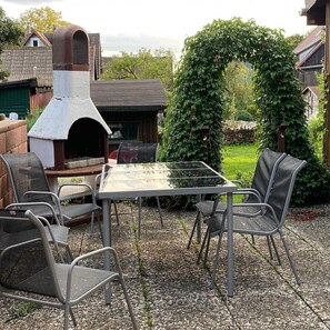 Een buitenpatio met een barbecue, stoelen en een tafel.