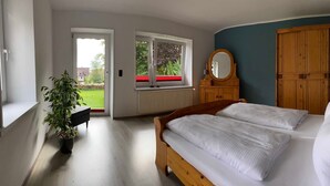 A bedroom with a bed, a dresser, a mirror, and a potted plant. - Apartment Hohensee ground floor - Ferienwohnung Hohensee (Clausthal-Zellerfeld)