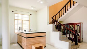 A hotel lobby with a reception desk, a staircase, and a large window. - Hip's House Homestay - Hostel (Phu Quoc)