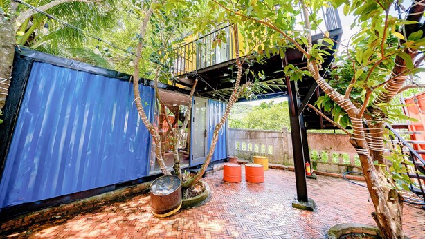 A courtyard with a blue metal fence, potted plants, and a brick floor. - Hip's House Homestay - Hostel (Phu Quoc)