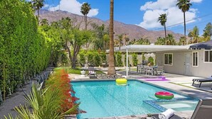 Ein Pool mit Liegestühlen, einer überdachten Terrasse und Palmen.