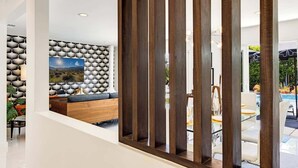 Ein modernes Interieur mit einer Eckcouch, einer Wand mit Muster und Blick ins Freie.