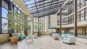 A spacious indoor area with multiple seating arrangements, large windows, and a glass ceiling. - Phoenix VII 212 | Beachfront | Heated Indoor Pool | My Beach Getaways (Orange Beach)