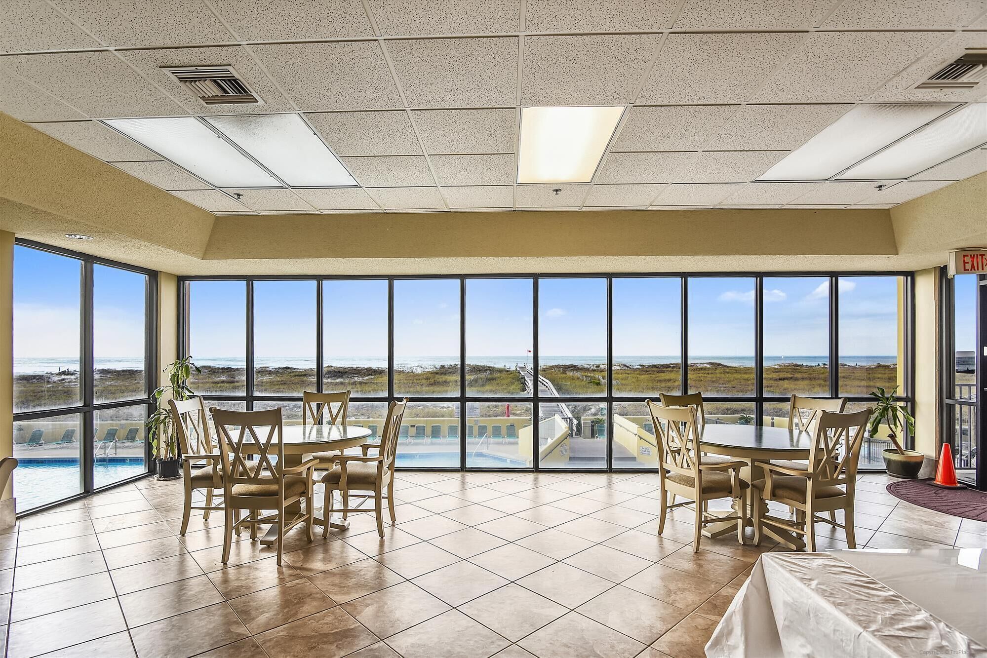 A spacious room with large windows offering a view of the beach and ocean.