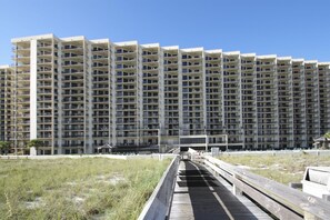 Un hotel de gran altura con varios balcones y un paseo marítimo que conduce a la entrada.