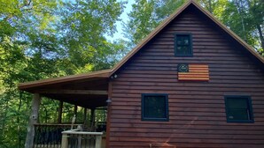 Una baita di legno con un portico, immersa tra gli alberi.