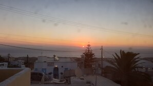 A sunset view from a rooftop with buildings and power lines in the foreground. -       BLUE SUITE     (Santorini)