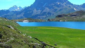 Un paysage montagneux avec un lac et une zone herbeuse.
