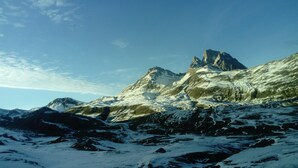 Un paysage montagneux aux sommets enneigés, sous un ciel dégagé.